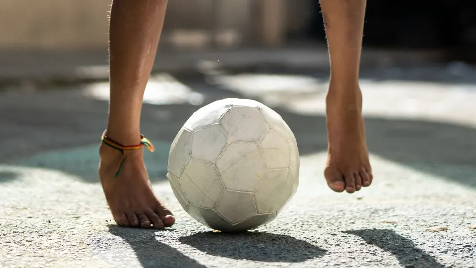 Ragazzo con maglia gialla e pantaloncini blu che gioca a calcio